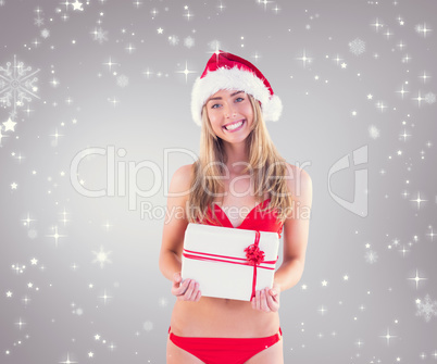 Composite image of festive fit blonde in red bikini showing gift