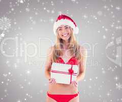 Composite image of festive fit blonde in red bikini showing gift