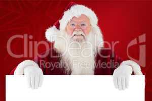 Composite image of santa looks over a sign
