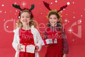 Composite image of festive little girls holding gifts