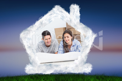 Composite image of couple lying on the floor and looking at hous