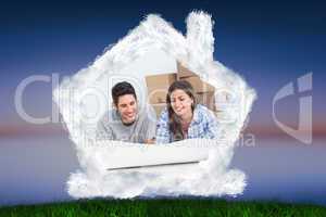 Composite image of couple lying on the floor and looking at hous