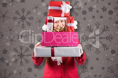 Composite image of festive redhead holding pile of gifts