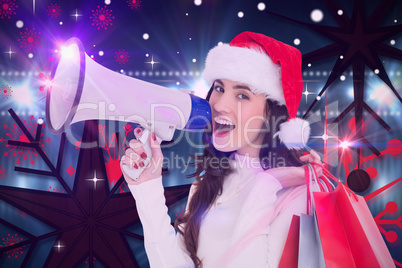 Composite image of festive brunette holding gift bags and megaph