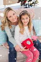 Composite image of daughter opening christmas gift with mother