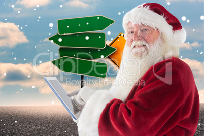 Composite image of santa uses a tablet pc and smiles into the ca