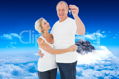 Composite image of mature couple smiling at camera with new hous