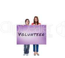 Composite image of smiling young women proudly holding a blank p