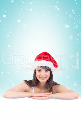 Composite image of festive brunette leaning on large poster