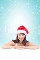 Composite image of festive brunette leaning on large poster