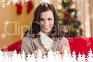 Composite image of brunette opening a gift on the couch at chris