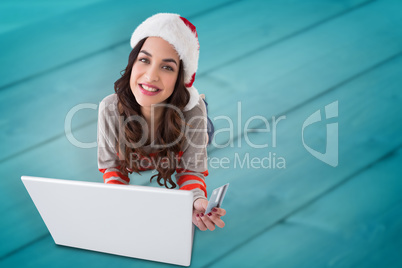 Composite image of happy brunette shopping online with laptop