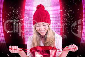 Composite image of pretty blonde opening gift bag