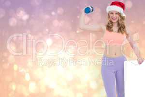 Composite image of festive fit blonde smiling at camera holding