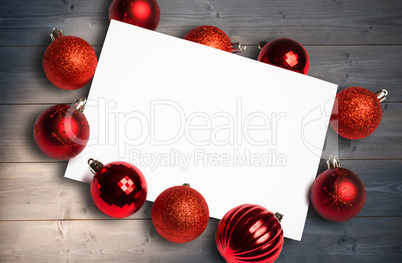 Composite image of red christmas baubles surrounding white page