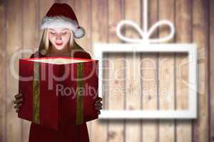 Composite image of festive blonde holding a gift