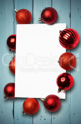 Composite image of red christmas baubles surrounding white page