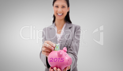 Composite image of money being put into piggy bank by smiling bu