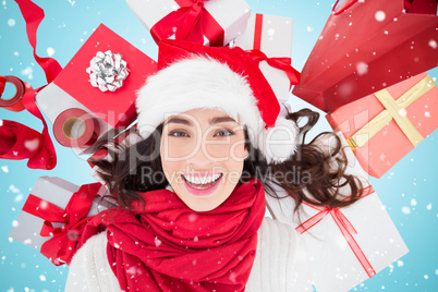 Composite image of festive brunette lying near christmas present