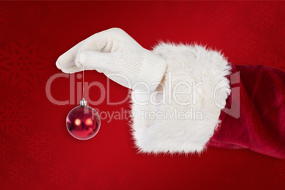 Composite image of santas hand is holding a christmas bulb