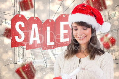 Composite image of festive brunette opening a gift