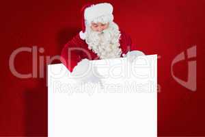 Composite image of cheerful santa claus presenting sign