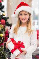 Composite image of festive little girl holding a gift