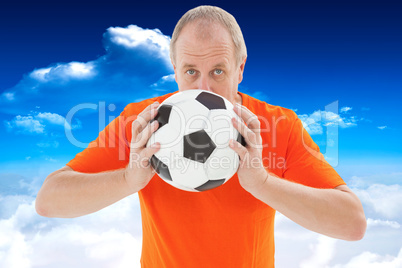 Composite image of nervous football fan holding ball