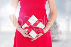 Composite image of woman in red dress holding gift