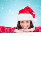 Composite image of beauty brunette in santa hat smiling at camer