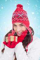 Composite image of surprised brunette in winter clothes holding