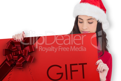 Composite image of beauty brunette in santa hat showing gift car