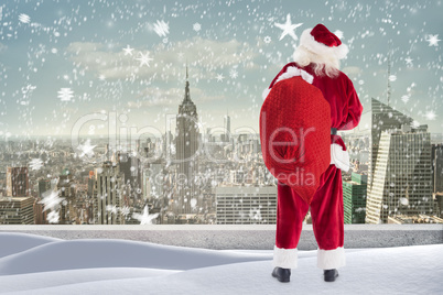 Composite image of santa standing on snowy ledge