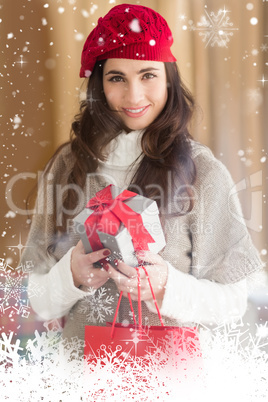 Composite image of smiling brunette holding gift and shopping bags