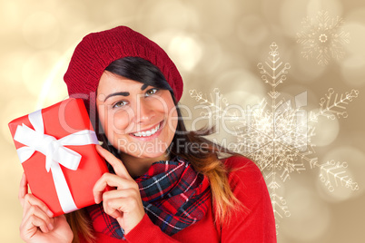 Composite image of smiling brunette in red hat holding gift