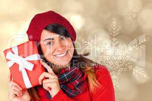 Composite image of smiling brunette in red hat holding gift