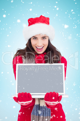 Composite image of festive brunette showing a laptop