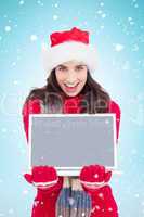 Composite image of festive brunette showing a laptop