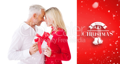 Composite image of smiling couple passing a wrapped gift