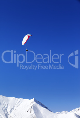 Paraglider in snowy mountains at nice sun day