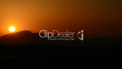Timelapse of sunset with sun and mountains