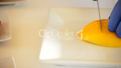 Hands of chef or professional chef cutting a mango tropical fruit pan