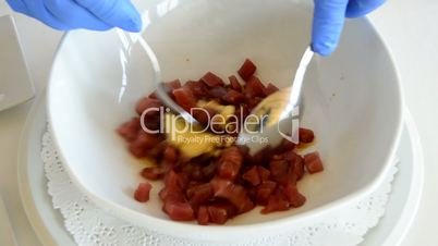 Hands of professional chef mixing ingredients like red fish and mustard in a bowl