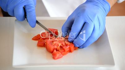 Professional chef hands cutting a tomato into small squares