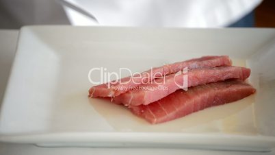 Professional chef hands cutting into pieces red fish fillets or tuna