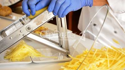 Professional chef hands cutting potatoes with knife and mandolin