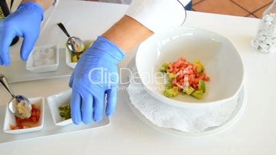 Professional chef hands mixing avocado, tomato, salt and chive, in a bowl