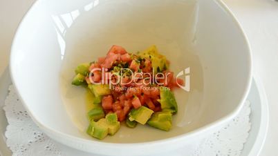 Professional chef hands mixing tomato avocado and other ingredients in a bowl