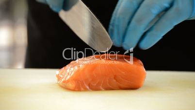 Professional chef hands cutting a salmon fillet