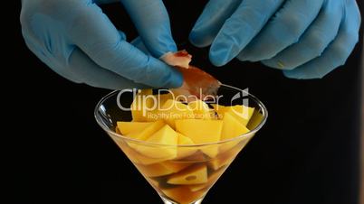 Professional chef hands placed on Spanish ham cup with diced mango fruit